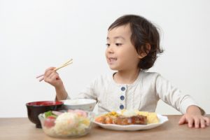 笑顔で食事をとっている子どもの画像
