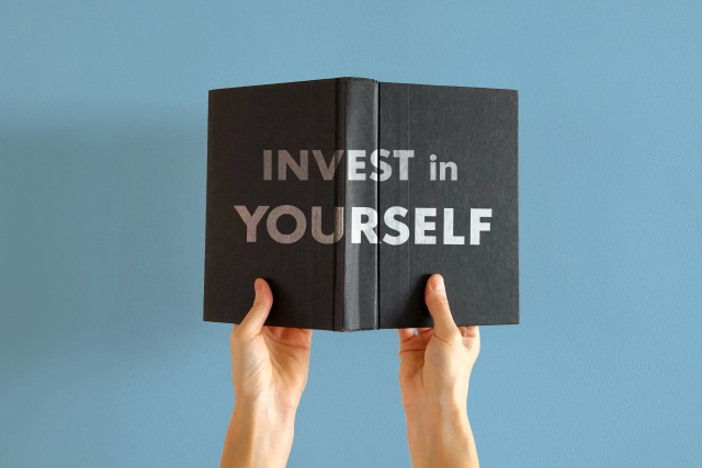 INVEST in YOURSELFと書かれた本を持つ手