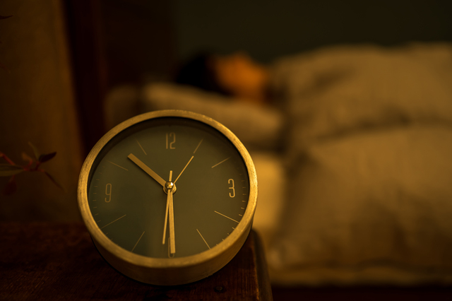 夜ベッドサイドにある時計の画像
