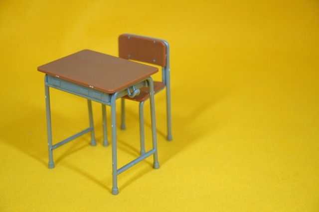 黄色の背景にミニチュアの机と椅子
